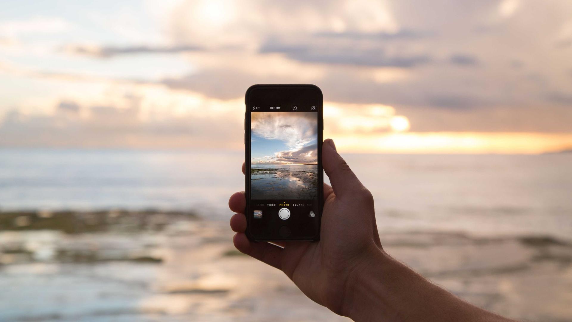 Editorial context photo of a phone held against an open horizon